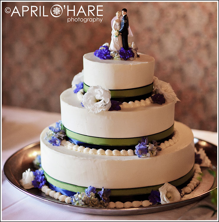 A delicious white cake with blue and white flowers and green ribbon